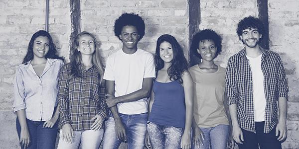 Group of teens standing against a wall smiling